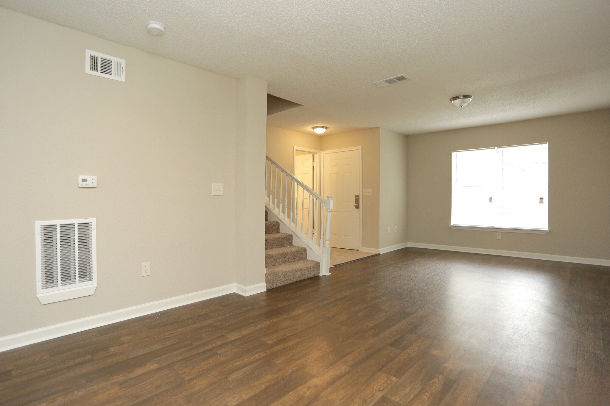 A room with wooden floors and a staircase leading to another room.